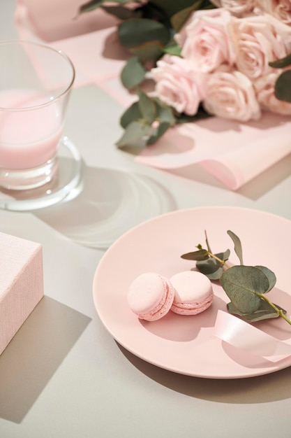 Macaroons em tons pastel com buquê de flores rosas em fundo branco