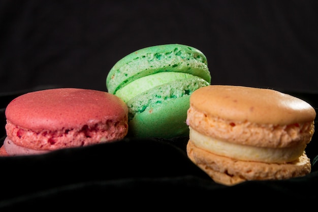 Macaroons em veludo preto. Isolado. Sobremesa francesa.