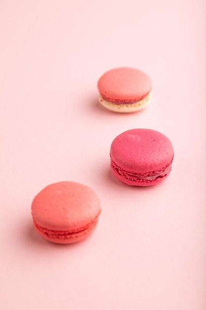 Macaroons magenta e rosa na vista lateral de fundo rosa pastel fechar