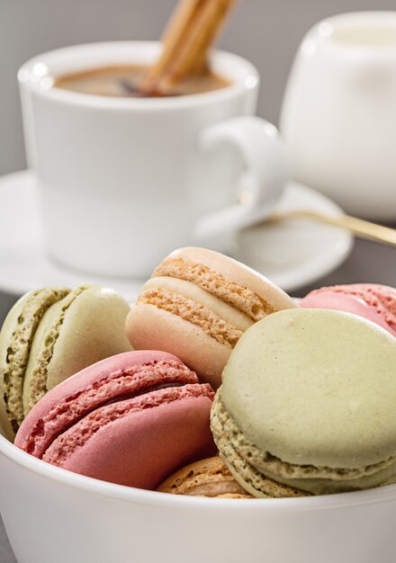 Macaroons multicoloridos e café quente com canela em pau