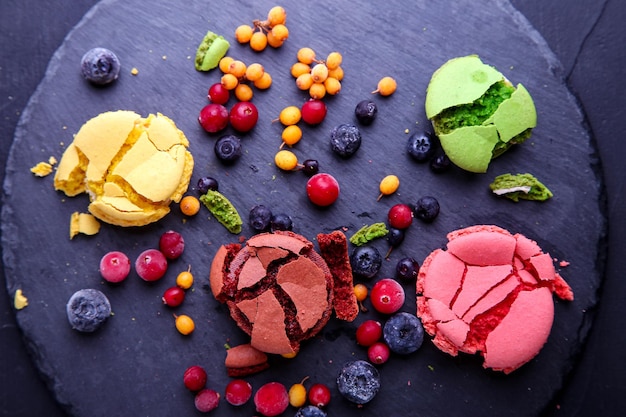 Macaroons quebrados com frutas congeladas em um fundo cinza.