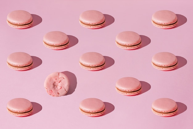 Foto macaroons rosa com padrão de creme de chocolate com sombras claras no fundo rosa da moda