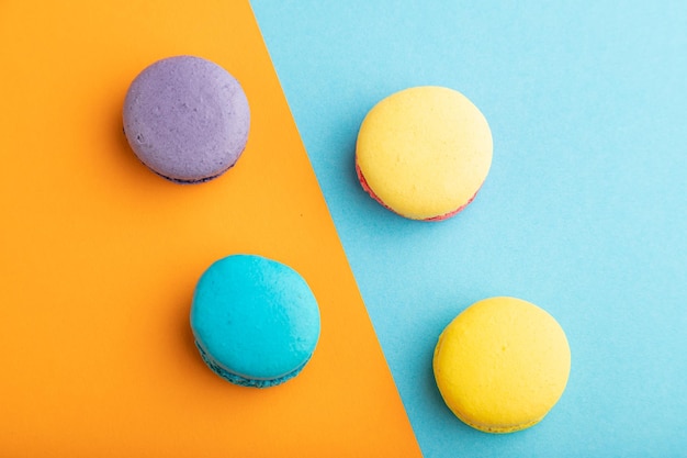 Macaroons roxos e azuis amarelos no espaço de cópia de vista superior de fundo pastel azul e laranja