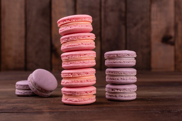 Macaroons saborosos rosa lindos em um fundo de madeira