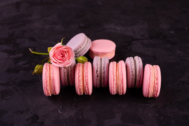 Macaroons saborosos rosa lindos sobre um fundo de concreto