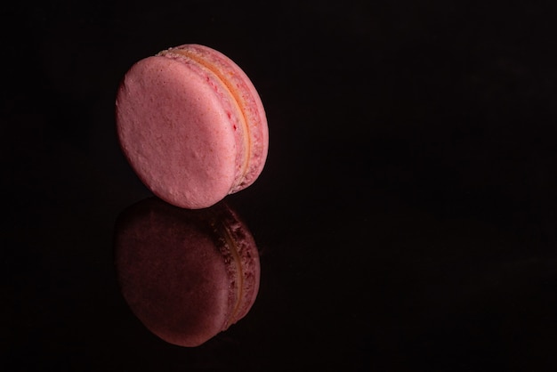 Macaroons saborosos rosa lindos sobre um fundo escuro