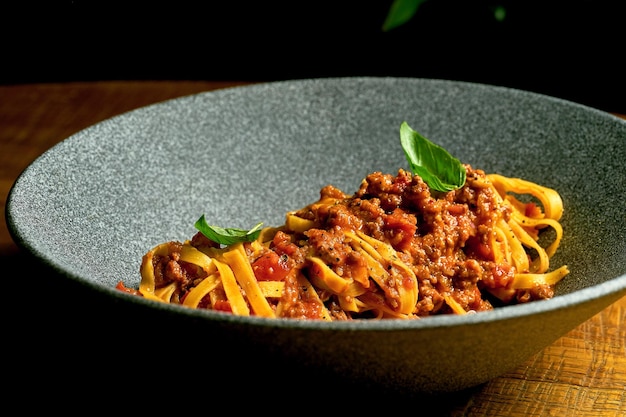 Macarrão à bolonhesa com molho vermelho de carne picada em uma tigela sobre uma placa de madeira