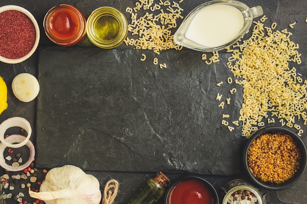 Macarrão alfabeto e ingrediente para o molho (conjunto de ingredientes, macarrão cru), servindo o segundo prato. fundo de comida superior. copie o espaço