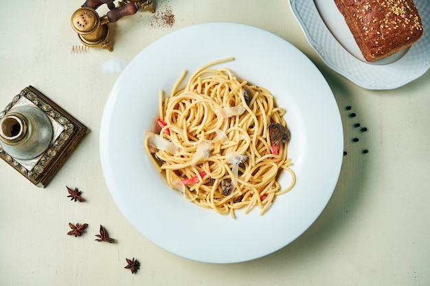 Macarrão apetitoso com legumes e parmesão em um prato branco sobre uma mesa de madeira. Cozinha italiana. Vista superior plana leigos alimentos.