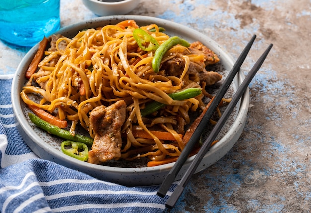 Macarrão asiático com carne de porco em molho teriyaki, com feijão verde, cenoura e cogumelos shiitake.