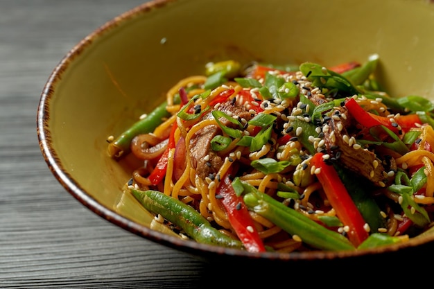 Macarrão asiático com carne, legumes, sementes de gergelim e molho teriyaki. Comida de rua - macarrão wok