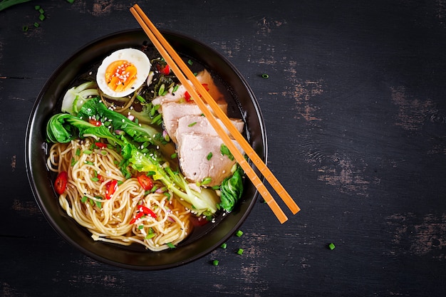 Macarrão asiático do Miso Ramen com ovo, carne de porco e couve de pak choi na bacia na superfície escura. Cozinha japonesa.