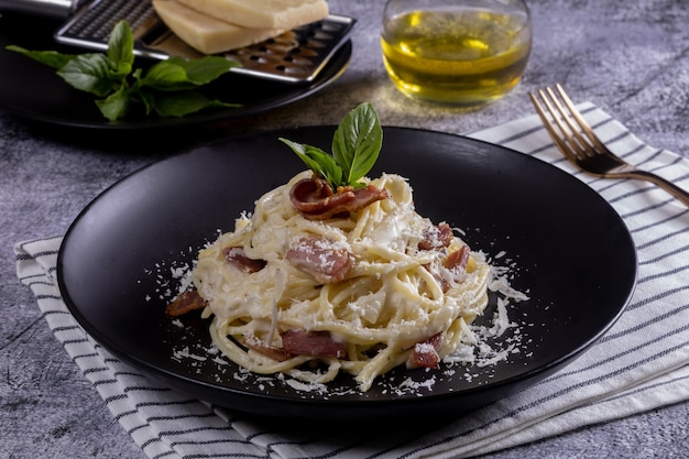 Macarrão Carbonara. Espaguete com bacon, queijo parmesão e queijo parmesão. Pasta Carbonara em chapa preta com parmesão. Comida italiana.