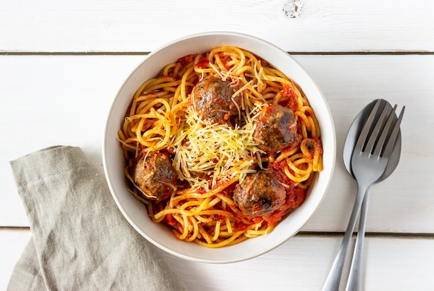 Macarrão com almôndegas e molho de tomate em um fundo de madeira.