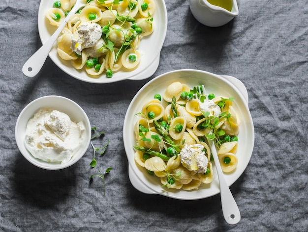 Macarrão com aspargos de ervilhas verdes e ricota fresca Em uma vista superior de fundo cinza Comida deliciosa saudável