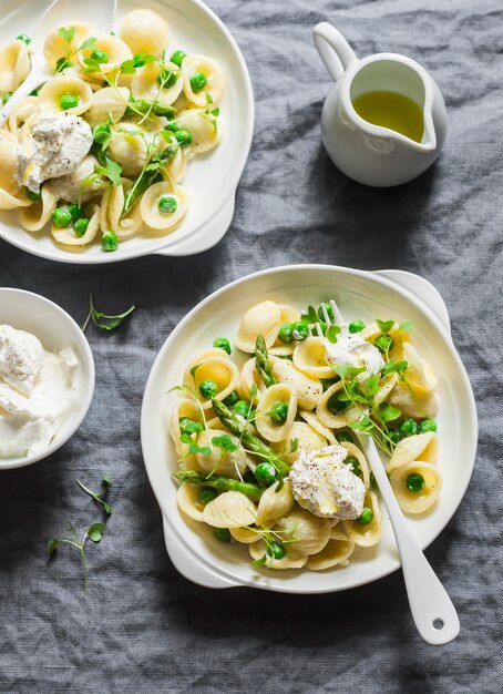 Macarrão com aspargos de ervilhas verdes e ricota fresca em uma vista superior de fundo cinza