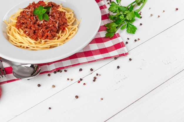 Macarrão com carne, molho de tomate e legumes em cima da mesa