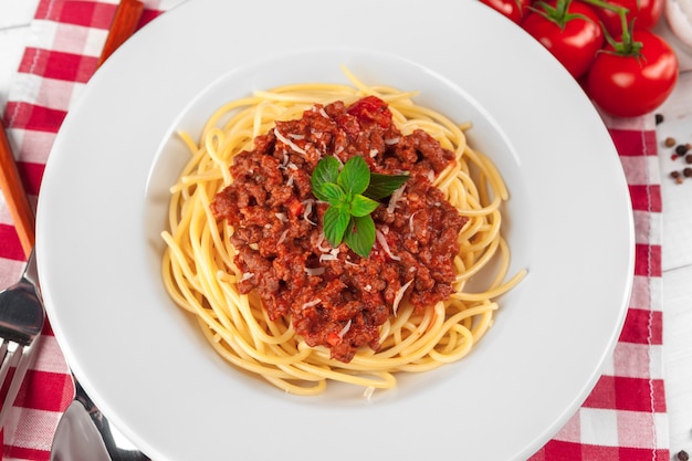 Macarrão com carne, molho de tomate e legumes em cima da mesa