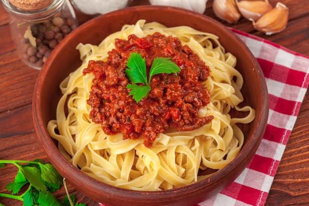 Macarrão com carne, molho de tomate e legumes em cima da mesa