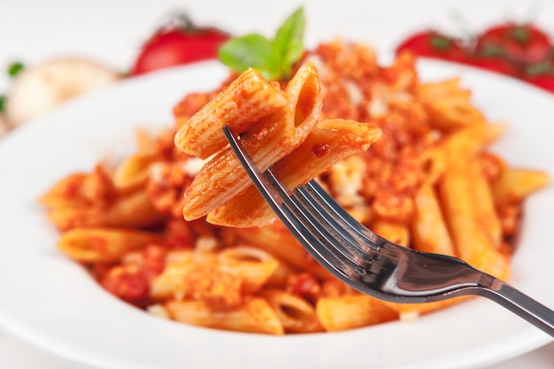 Macarrão com carne, molho de tomate e legumes em cima da mesa