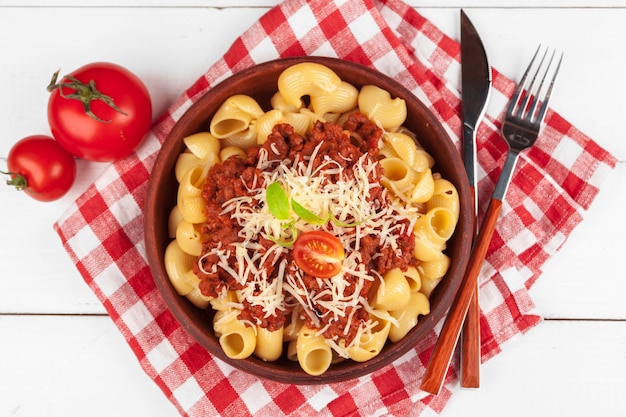 Macarrão com carne, molho de tomate e legumes em cima da mesa