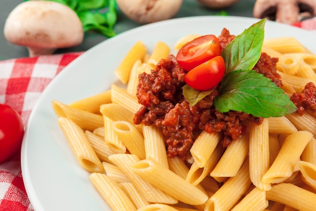 Macarrão com carne, molho de tomate e legumes em cima da mesa