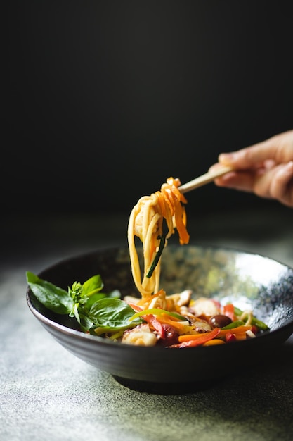 Macarrão com frutos do mar e legumes em um fundo escuro. Comida asiática.