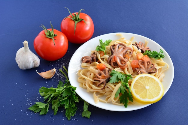 macarrão com frutos do mar e tomate na chapa branca no fundo azul escuro