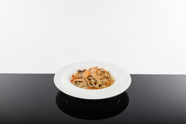 Foto macarrão com frutos do mar em mesa preta com fundo branco