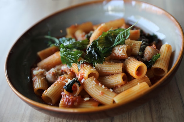 Macarrão com linguiça em molho de tomate na madeira, comida italiana