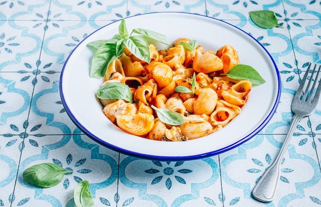 Macarrão com molho de tomate de cogumelos e manjericão no fundo da telha