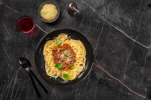 macarrão com molho de tomate queijo parmesão e manjericão em um prato em uma mesa escura Vista superior