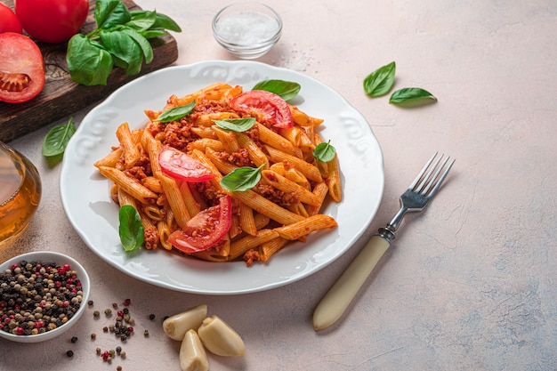 Macarrão com molho de tomate, tomate e manjericão em um fundo cinza claro. prato italiano. vista lateral, copie o espaço.