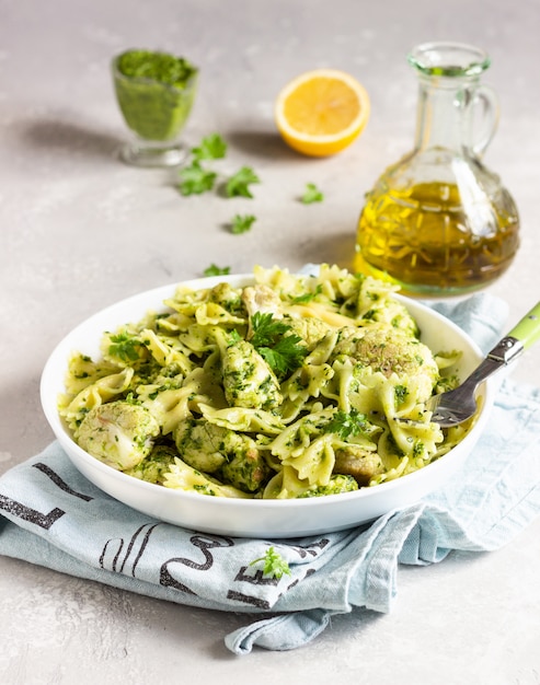 Macarrão com molho verde e couve-flor torrador num prato branco. Copie o espaço.