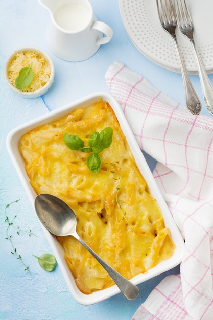 Macarrão com queijo. Caçarola de macarrão, queijo e molho bechamel em forma de cerâmica sobre concreto leve ou pedra.