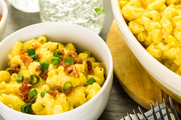 Macarrão com queijo guarnecido com pedaços de bacon e cebolinha.