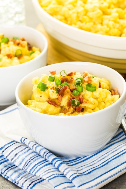 Macarrão com queijo guarnecido com pedaços de bacon e cebolinha.