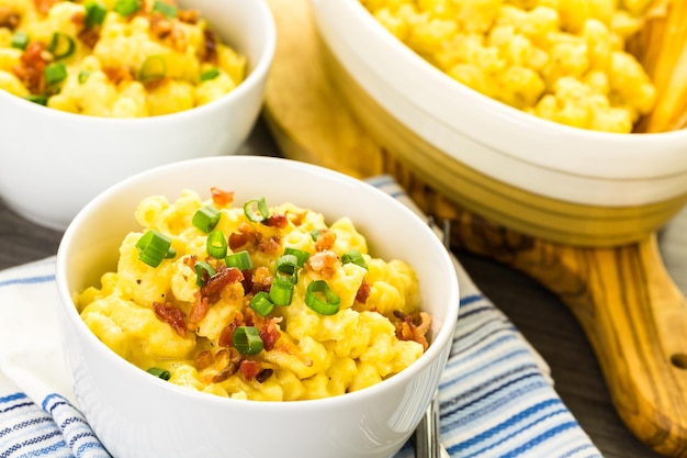 Macarrão com queijo guarnecido com pedaços de bacon e cebolinha.