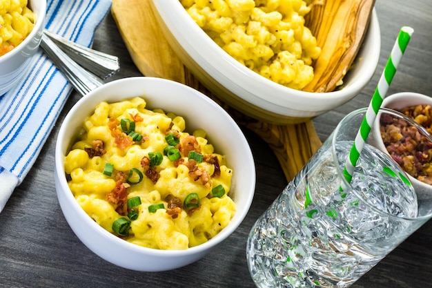 Macarrão com queijo guarnecido com pedaços de bacon e cebolinha.