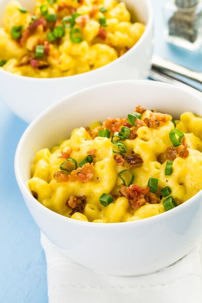 Macarrão com queijo guarnecido com pedaços de bacon e cebolinha.