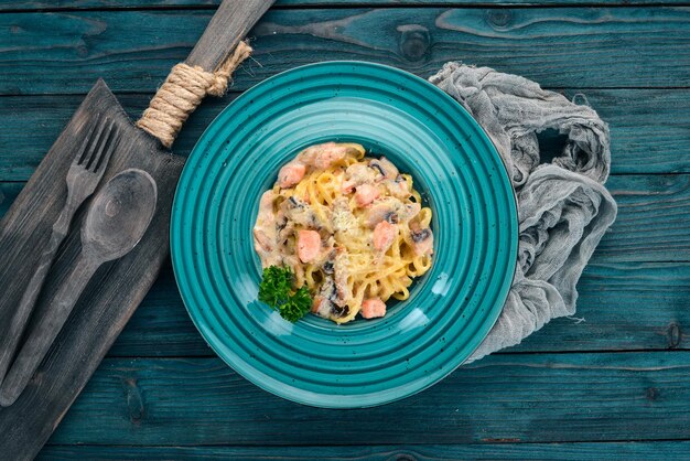 Macarrão com salmão e cogumelos Cozinha italiana Em um fundo de madeira Vista superior Copiar espaço