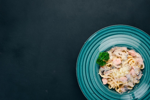 Macarrão com salmão e cogumelos Cozinha italiana Em um fundo de madeira Vista superior Copiar espaço