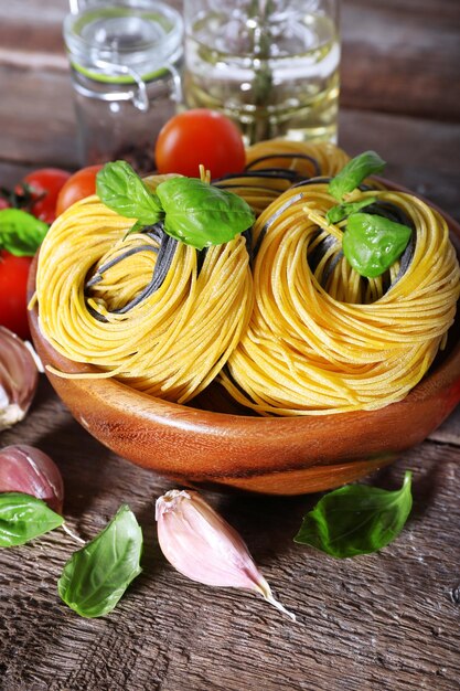 Macarrão com tomate cereja e outros ingredientes no fundo da mesa de madeira