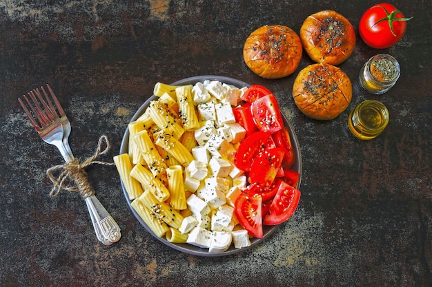 Macarrão com tomate e queijo branco. tigela vegetariana com macarrão, tomate e queijo feta. pãezinhos com azeite. comida saudável estilo italiano.
