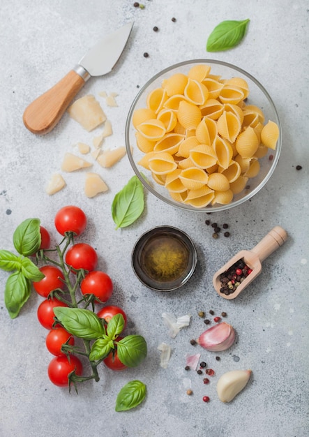 Macarrão Conchiglie em tigela de vidro com queijo parmesão e óleo de tomate e alho com manjericão sobre fundo claro Vista superior