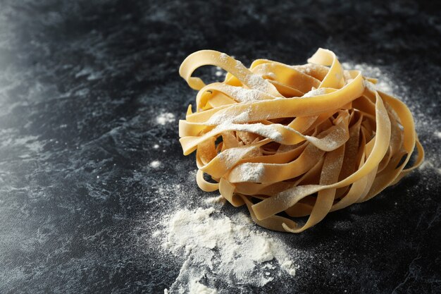 Macarrão cru com farinha em superfície preta esfumada