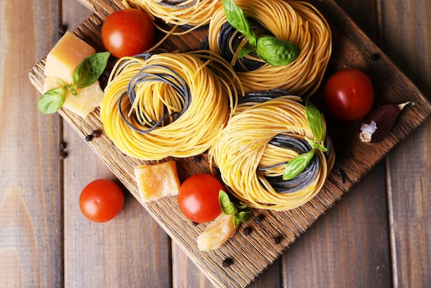 Macarrão cru com queijo e legumes em fundo de madeira