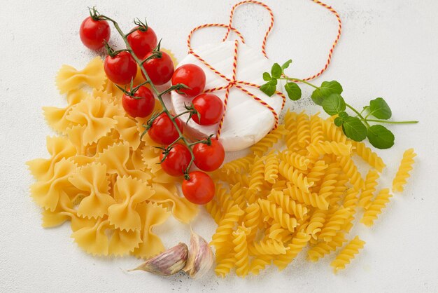 Foto macarrão cru cru com tomate cereja no fundo branco