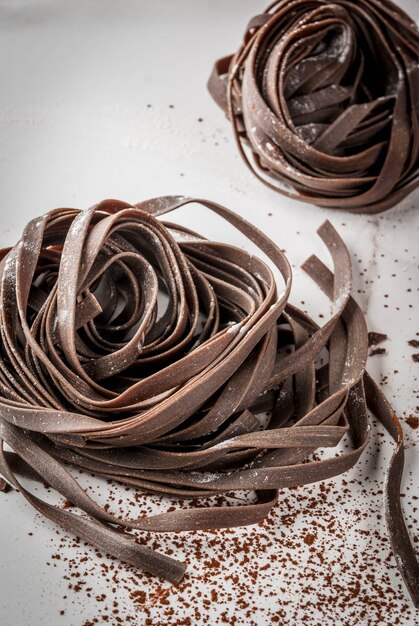Foto macarrão cru despreparado da massa do chocolate. em uma mesa de mármore branca da cozinha.