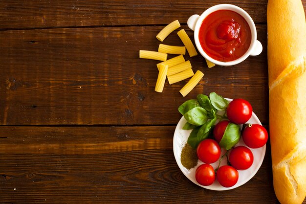 Macarrão cru e molho de sabor na tigela e tomate cereja fresco vermelho para preparar o café da manhã